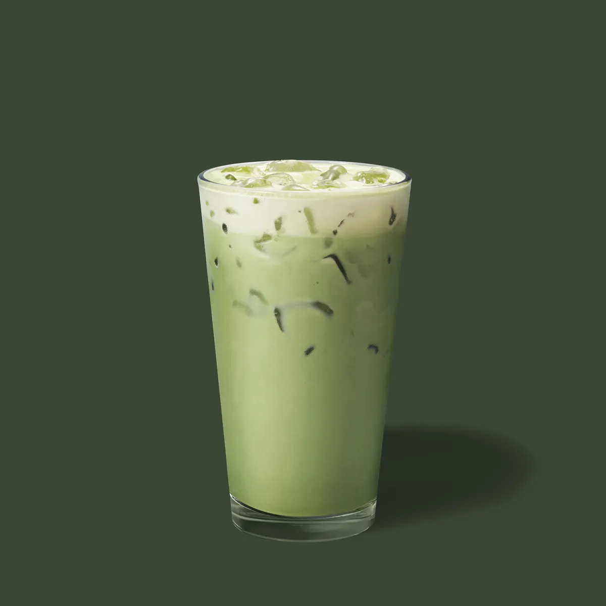 Iced Matcha Latte dans un grand verre transparent sur fond vert