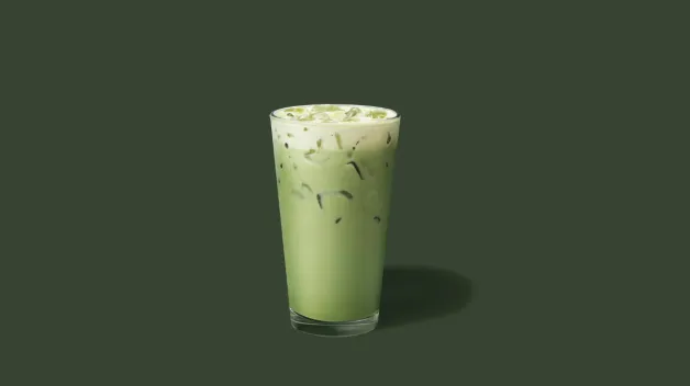 Iced Matcha Latte dans un grand verre transparent sur fond vert